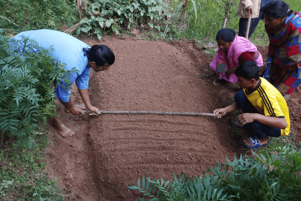 A group of people in the dirt with a stick.