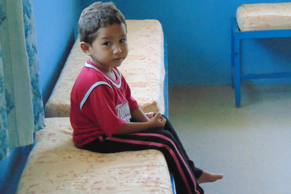 A young boy sitting on top of a bed.