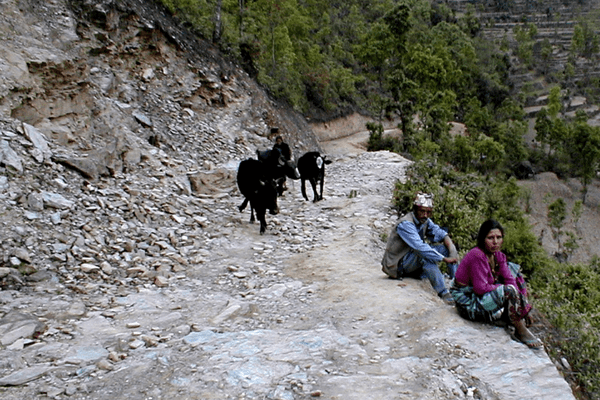 A couple of people sitting on the side of a road.