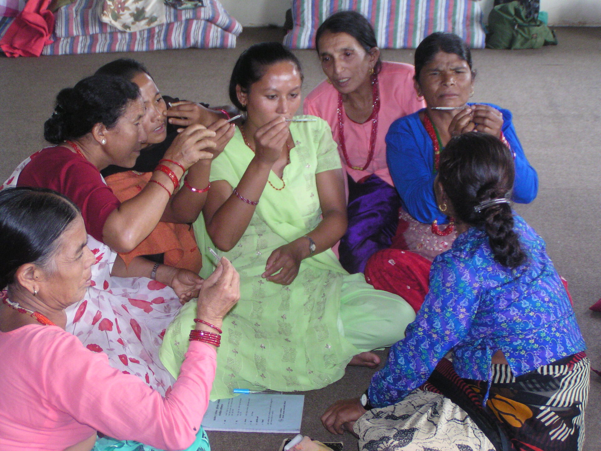 A group of women sitting on the ground talking.
