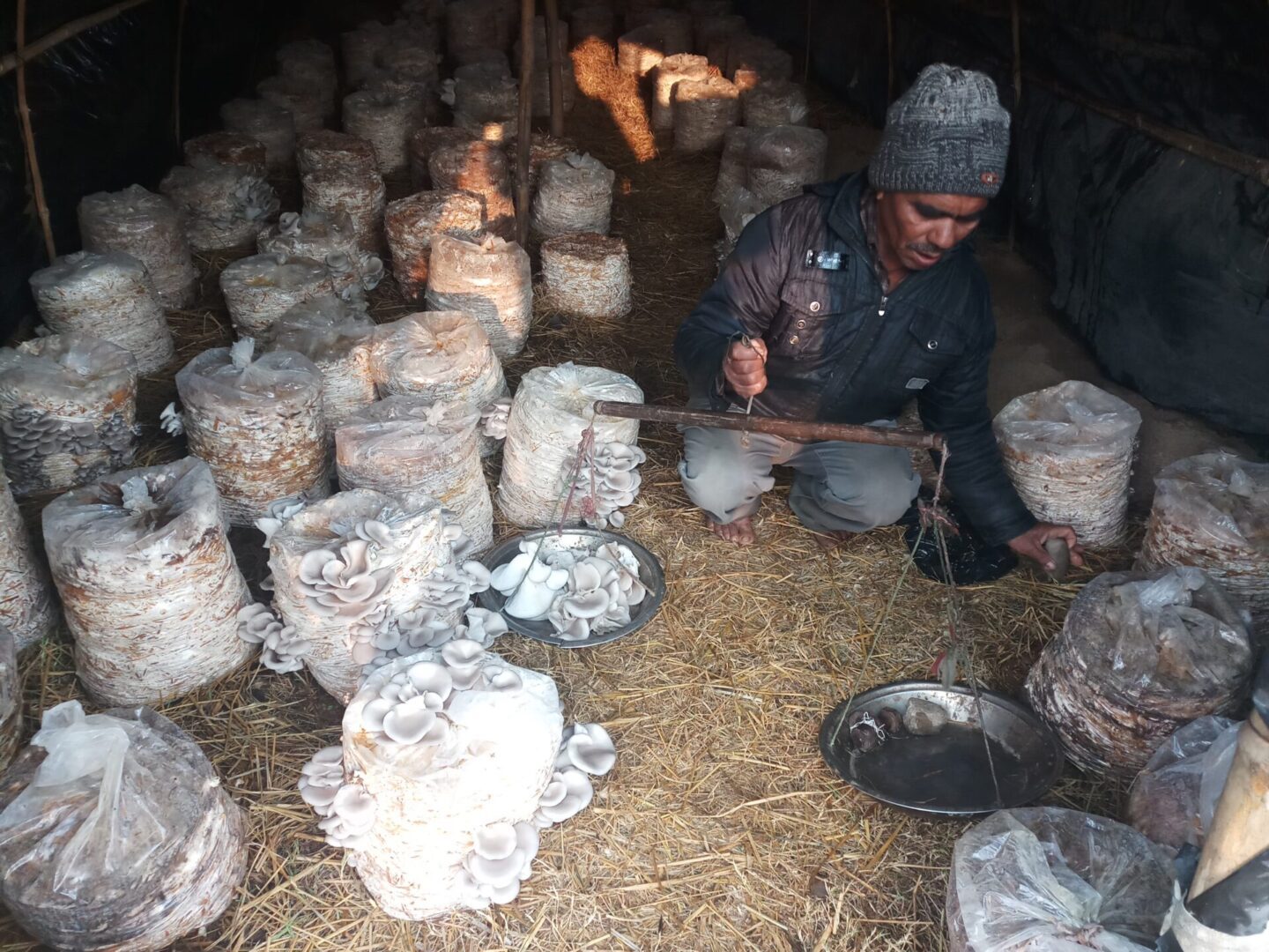 A man sitting in the dirt with many pots.