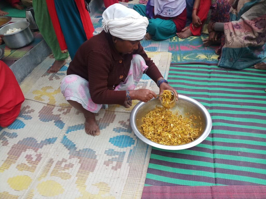 A woman is sitting on the ground and putting food into a bowl.