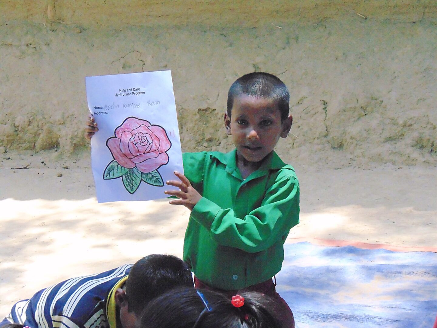 A boy holding up a drawing of a rose.