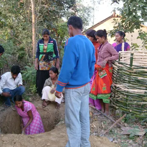 A group of people gathered around in the dirt.