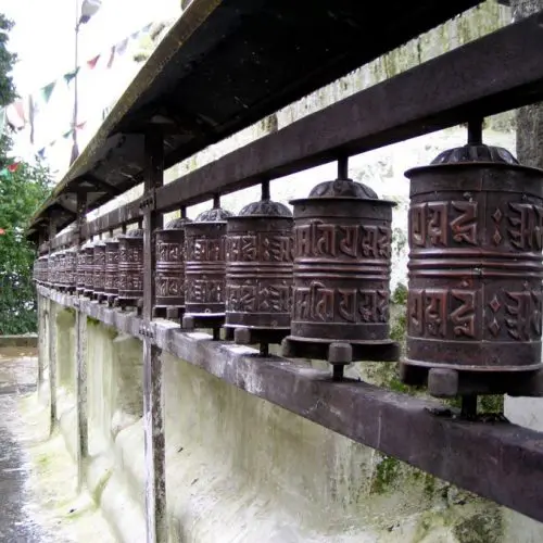 A row of prayer wheels on the side of a wall.