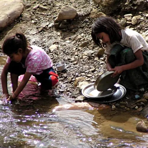 Two children playing in a stream with rocks.